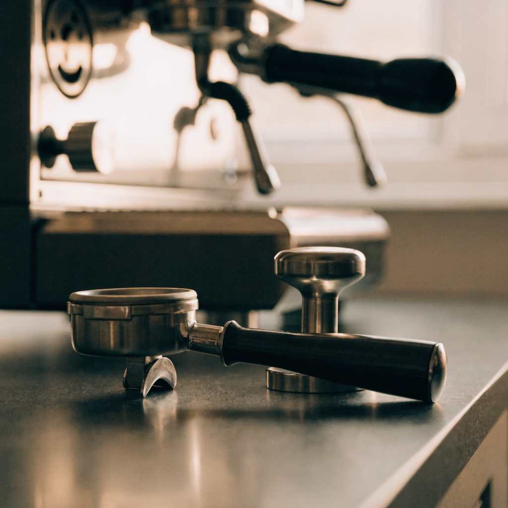 Portafilter and tamper beside an espresso machine