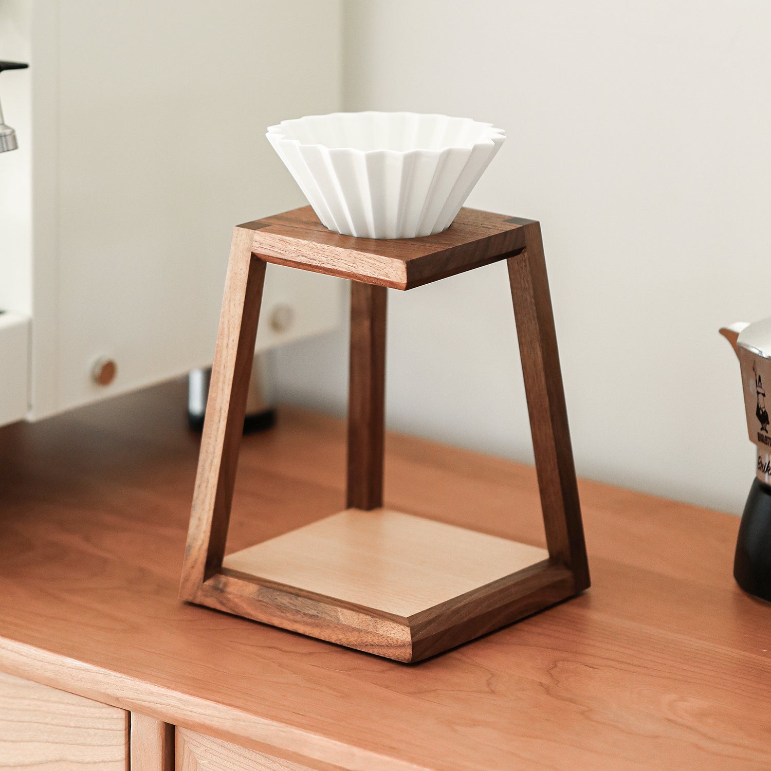 Solid wood trapezoid pour-over coffee stand on a wooden counter with a dripper resting on top
