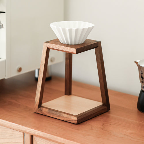 Solid wood trapezoid pour-over coffee stand on a wooden counter with a dripper resting on top
